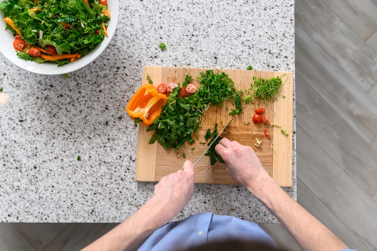 A person cuts the vegetables on the chopping board. Image via OGarden
